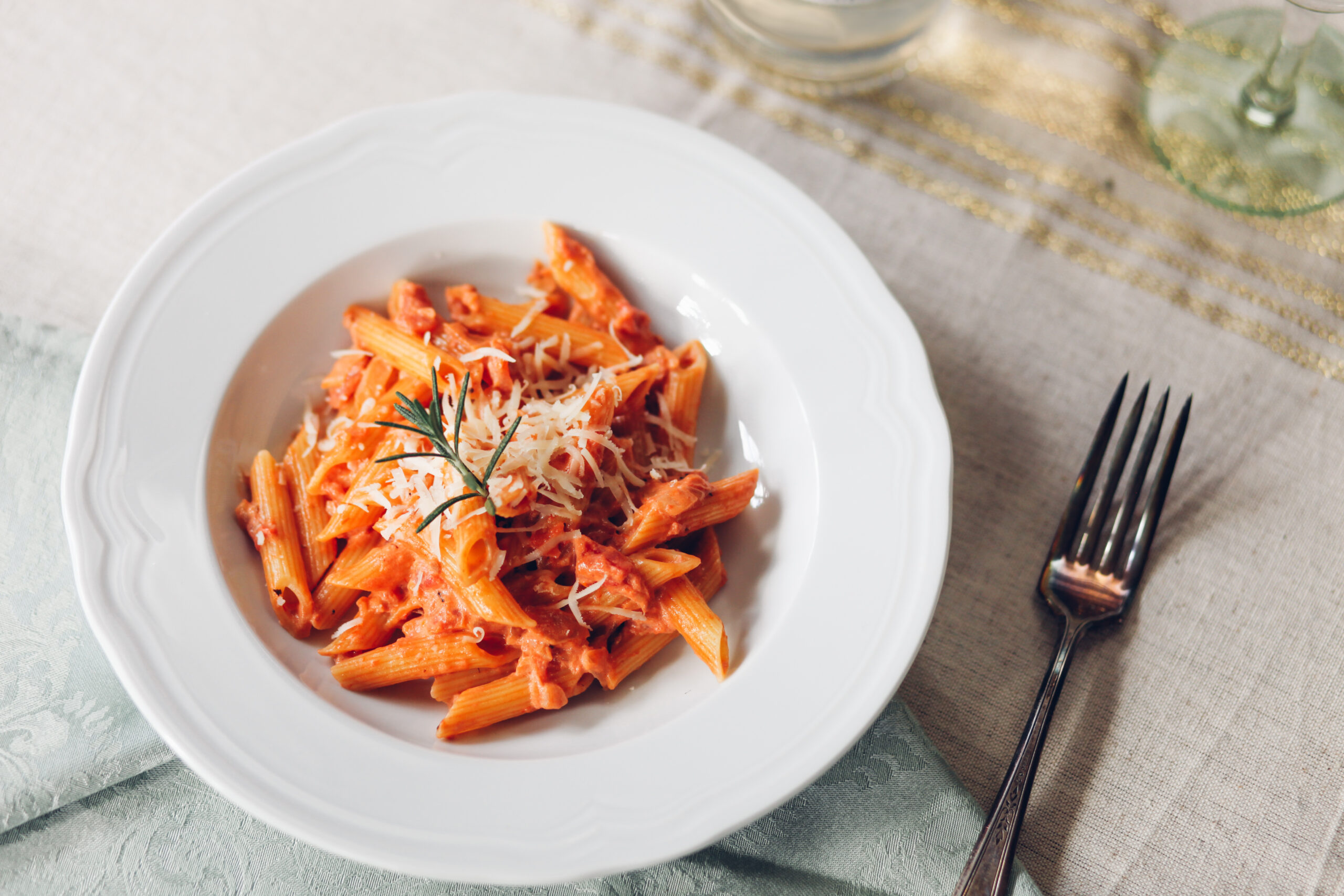 penne alla vodka pasta sauce with rosemary in white bowl
